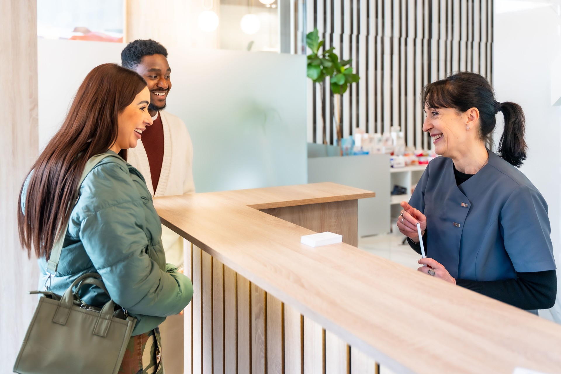 Couple smiling while talking to receptionist at dental clinic