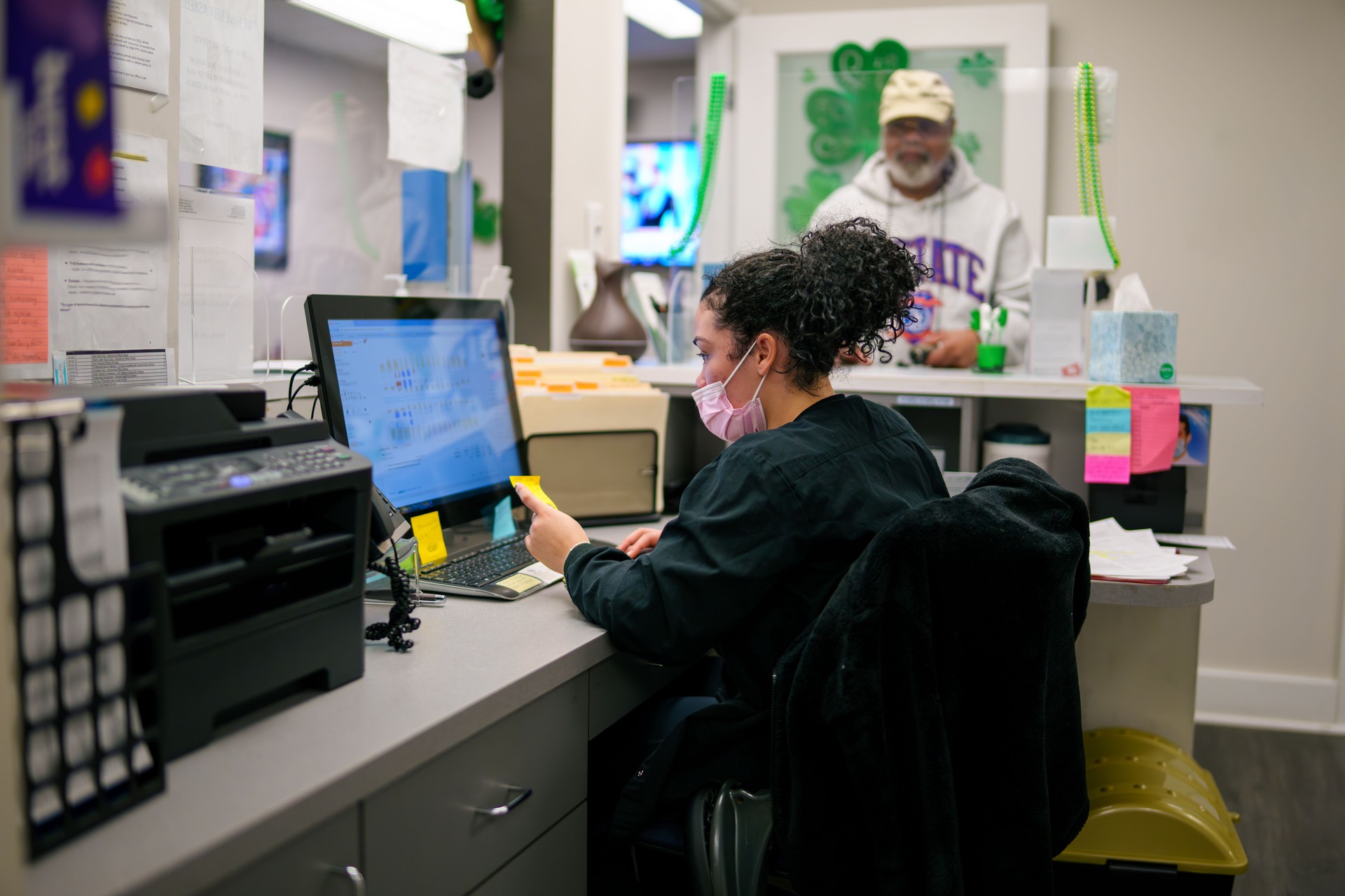 Female secretary checks man in to dentist appointment.